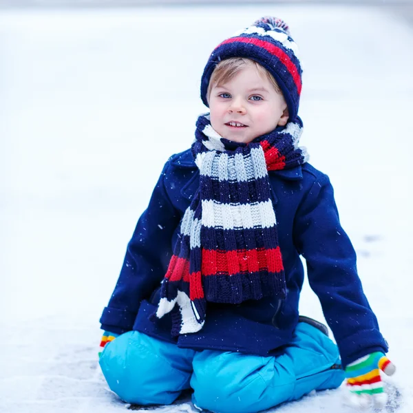 Schattige kleine grappige jongen in kleurrijke winterkleren met plezier met — Stockfoto