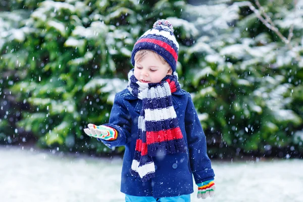 Cute little funny boy in colorful winter clothes having fun with — Stock Photo, Image