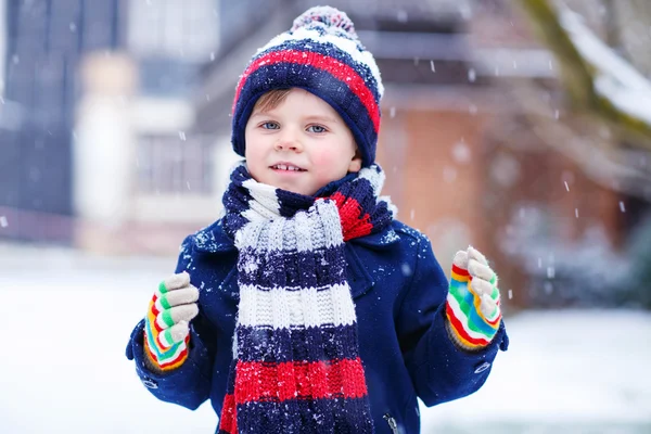 Cute little funny boy in colorful winter clothes having fun with — Stock Photo, Image
