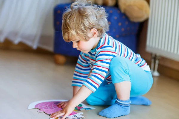 Piccolo ragazzo biondo carino che gioca con puzzle game a casa — Foto Stock