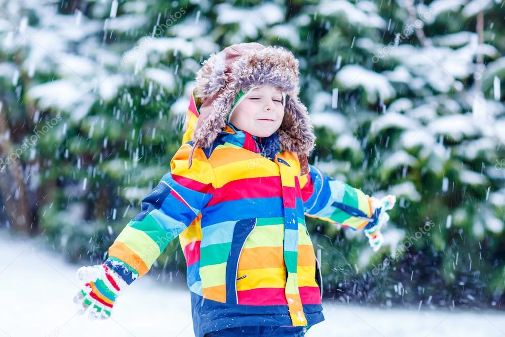 Cute little funny boy in colorful winter clothes having fun with