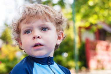 su ile dışarıda oynarken sevimli sarışın yürümeye başlayan çocuk.