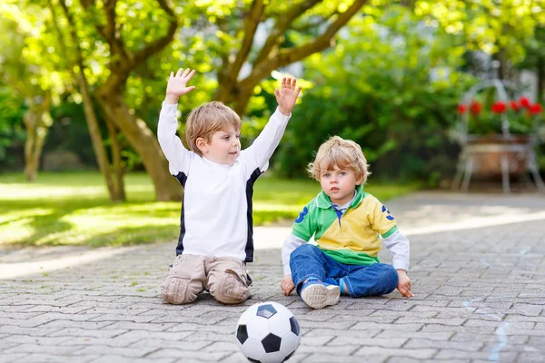 Two little sibling boys playing soccer and football — Stock Photo, Image