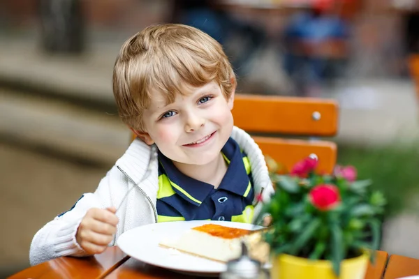 Liten unge pojke, skrattar och äta kakan i utanför café — Stockfoto