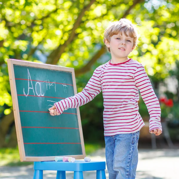 Petit garçon au tableau noir apprenant à écrire — Photo