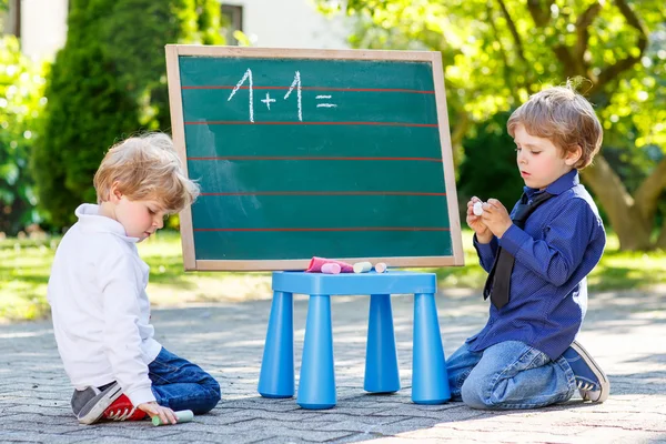 Deux garçons frères et sœurs au tableau noir pratiquant les mathématiques — Photo