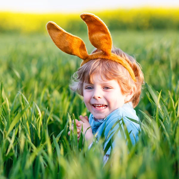 Petit garçon mignon avec des oreilles de lapin de Pâques dans l'herbe verte — Photo