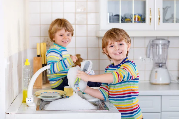 Zabawny podwójne chłopców pomaga w kuchni z mycia naczyń — Zdjęcie stockowe
