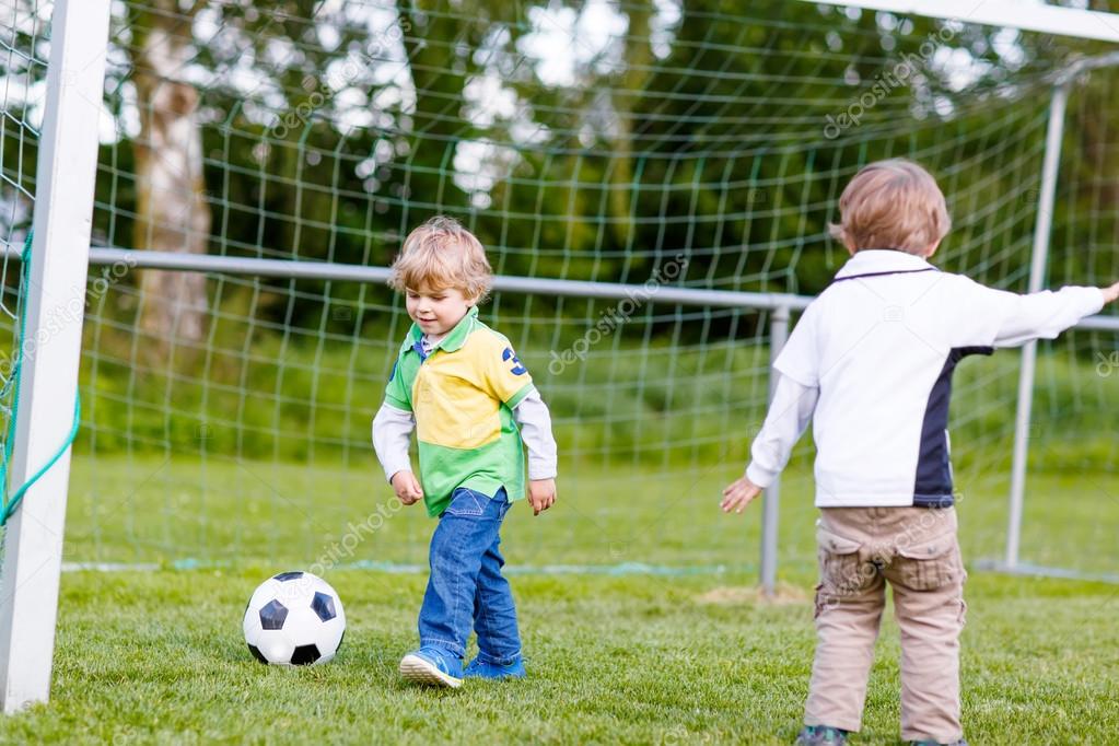 Two little sibling boys playing soccer and football