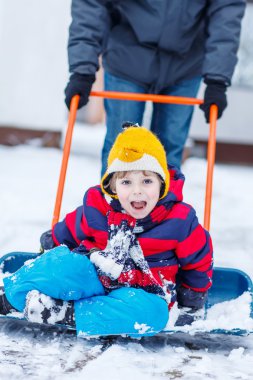 Komik çocuk çocuk kar küreği üzerinde açık havada sürme ile eğleniyor