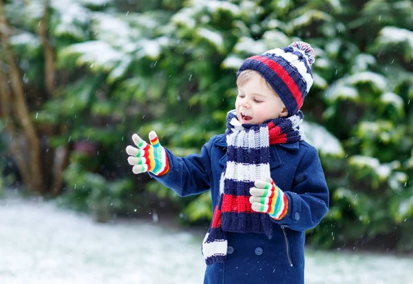 Liten pojke leker med snö på vintern, utomhus. — Stockfoto