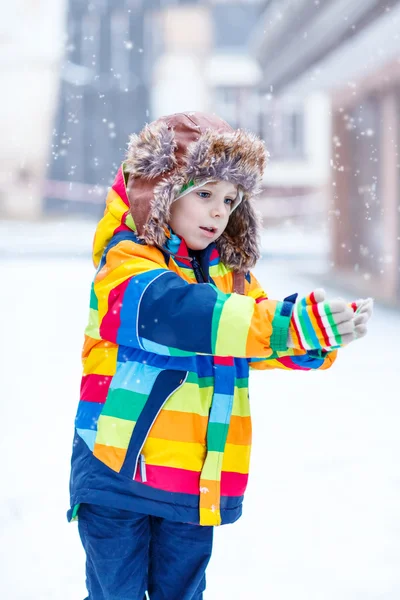 Kleine jongen spelen met sneeuw in de winter, buitenshuis. — Stockfoto