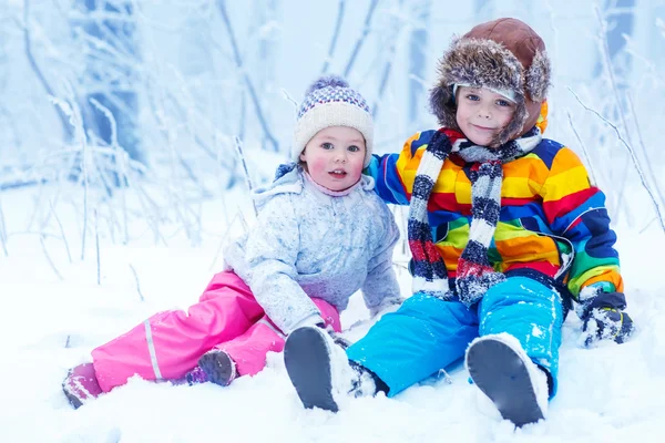 Retrato de menina e menino no chapéu de inverno na floresta de neve em — Fotografia de Stock