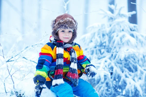 Söt liten rolig pojke i färgglada vinterkläder har roligt med — Stockfoto