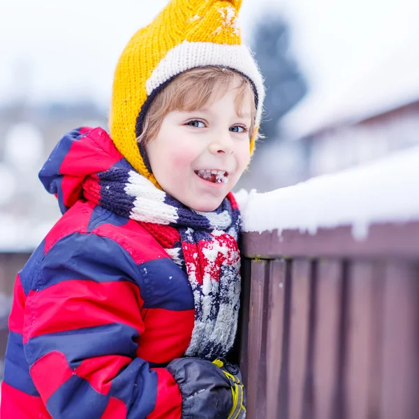 Маленький мальчик ест и пробует снег, на открытом воздухе в холодный день — стоковое фото