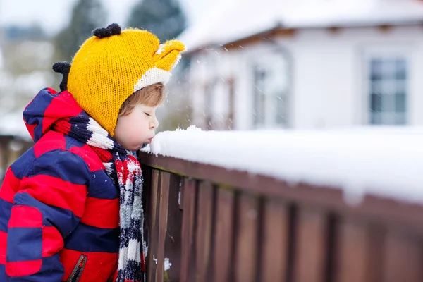 Niño pequeño en ropa colorida feliz por la nieve, al aire libre —  Fotos de Stock