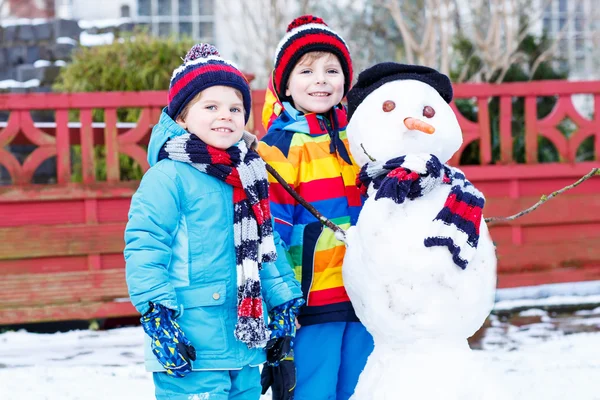 Deux petits frères et sœurs garçons faisant un bonhomme de neige, jouant et ayant fu — Photo