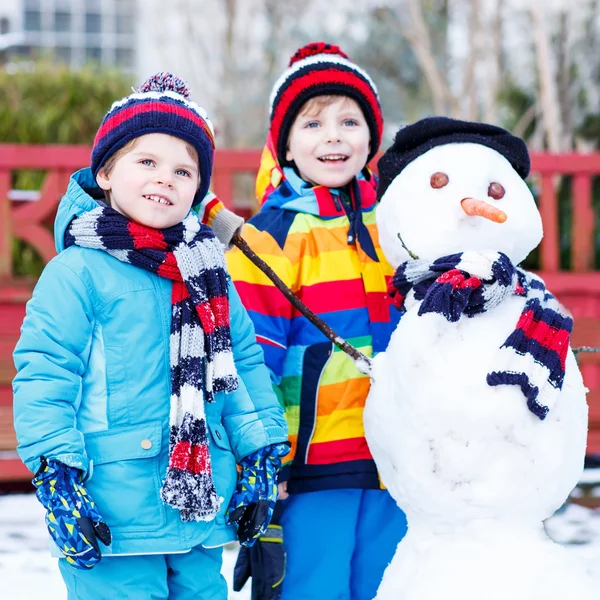 Dos amiguitos haciendo un muñeco de nieve, jugando y divirtiéndose con — Foto de Stock