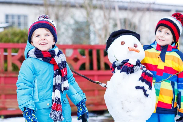 Two little siblings boys making a snowman, playing and having fu — Stock Photo, Image