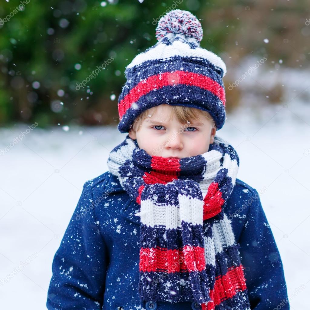 Sad kid boy in colorful winter clothes having fun with snow, out Stock  Photo by ©romrodinka 64900353