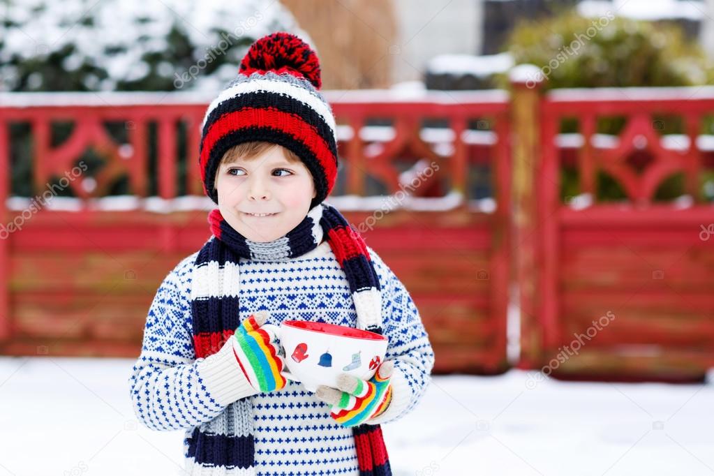 Funny little child holding big cup with snowflakes and hot choco