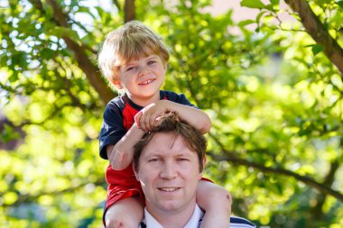 Çocuk parkta onun omuzlarında taşıyan baba