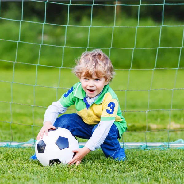 Två små syskon pojkar spelar fotboll och fotboll på fältet — Stockfoto