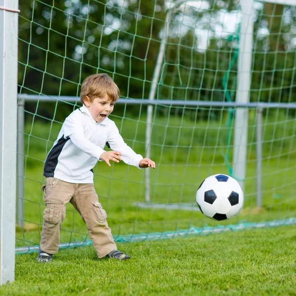 Two little sibling boys playing soccer and football on field — Stock Photo, Image