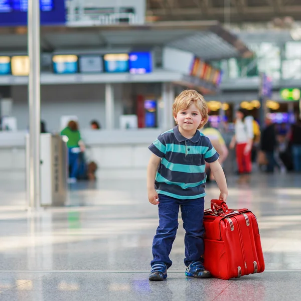 Liten pojke går på semester resa med resväska på flygplats — Stockfoto