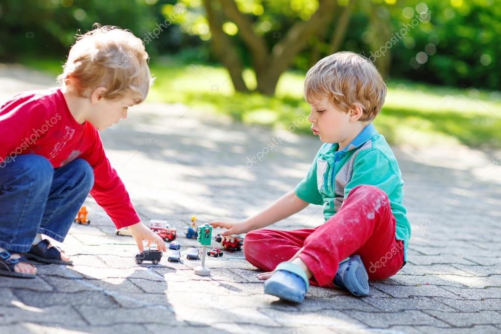 Two little kid boys playing with car toys