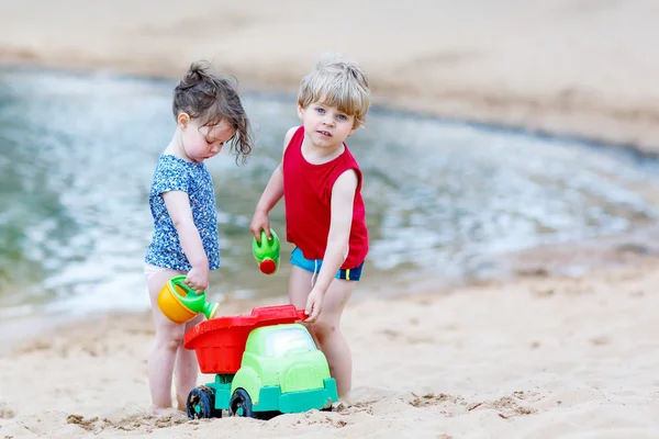 Pequeño niño y niña jugando juntos con juguetes de arena cerca — Foto de Stock