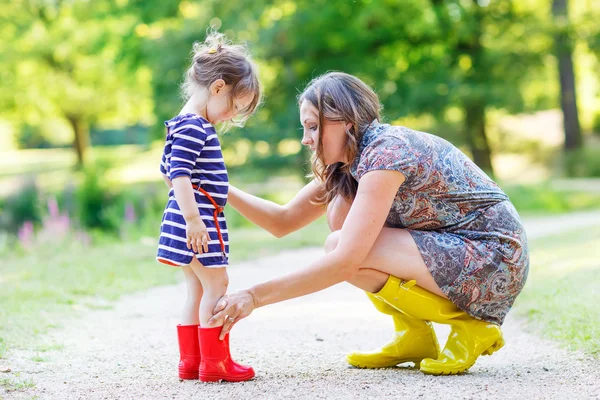 Mother and little adorable child girl in rubber boots having fun — Stock Photo, Image