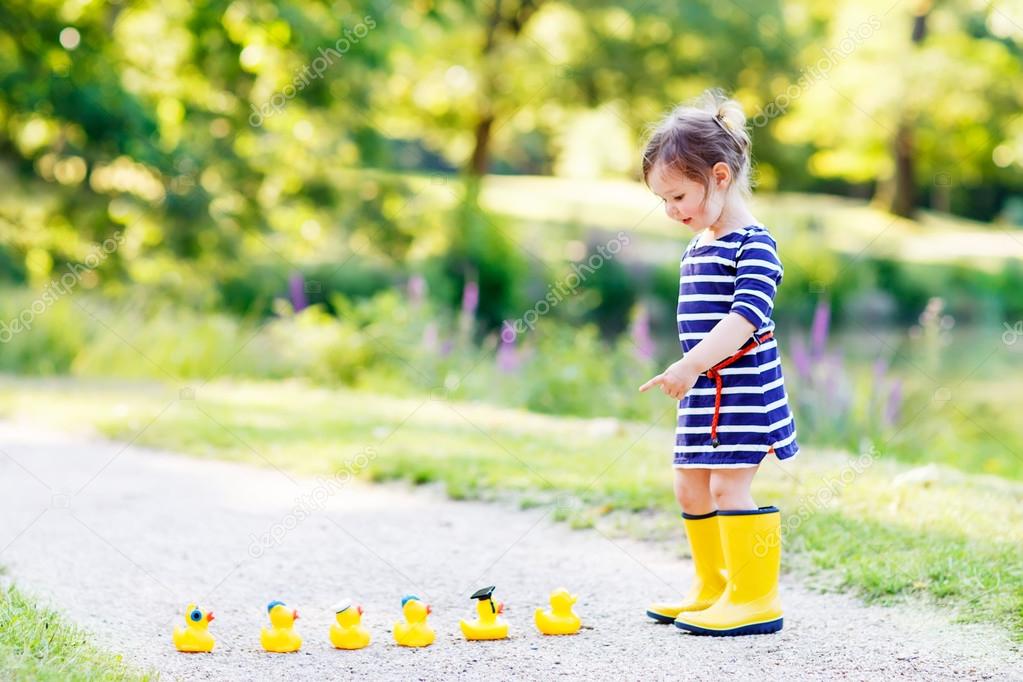 Adorable little child of 2 playing with yellow rubber ducks in s