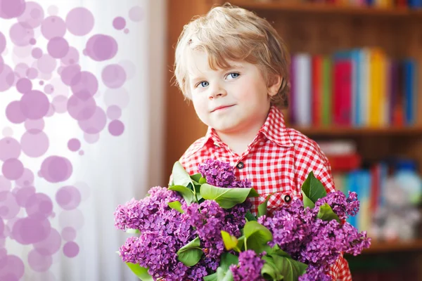 Adorable smiling little boy with blooming purple lilac flowers — Stock Photo, Image