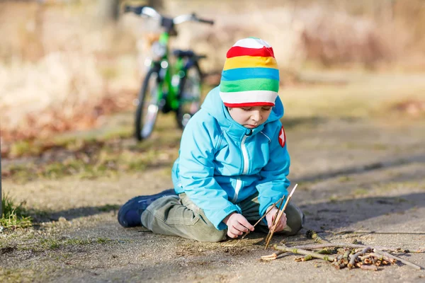 Bonito menino brincando com paus de madeira no parque da cidade, ao ar livre — Fotografia de Stock