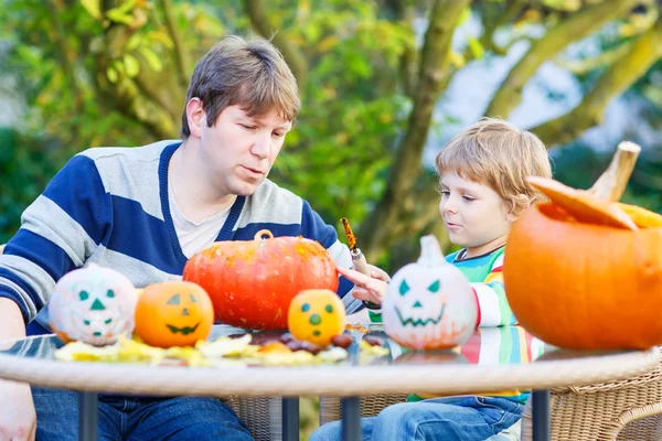 Mladý otec a jeho malý syn dělat jack-o lucernou pro halloween — Stock fotografie