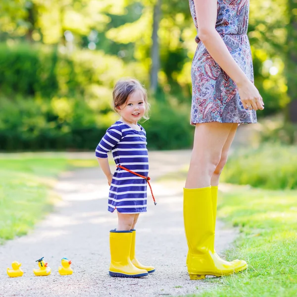 Mother and little adorable child in yellow rubber boots — Stock Photo, Image