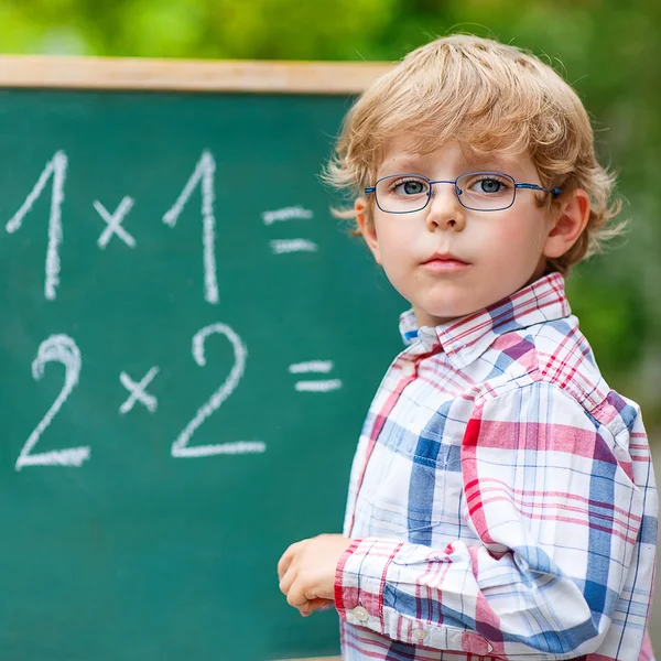 Niño preescolar con gafas en pizarra practicando matemáticas —  Fotos de Stock