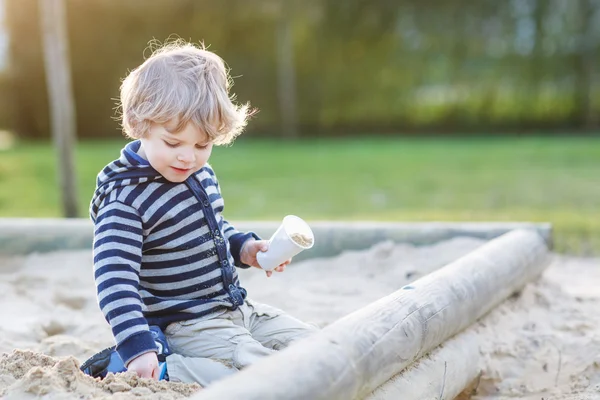 可爱的蹒跚学步的男孩在户外操场上玩沙子 — 图库照片