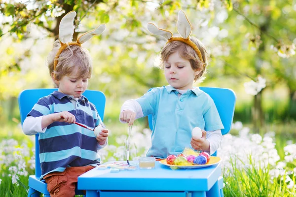 Dois meninos irmãos em orelhas de coelho de Páscoa colorir ovos — Fotografia de Stock