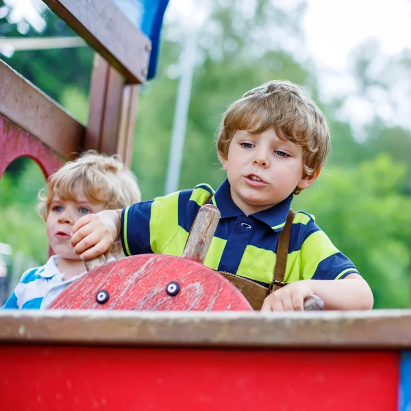 Two kid boys pretends driving an imaginary car on playground, — Stock Photo, Image