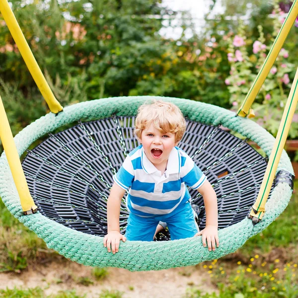 Adorável criança menino ter divertido cadeia swing no playgroun ao ar livre — Fotografia de Stock