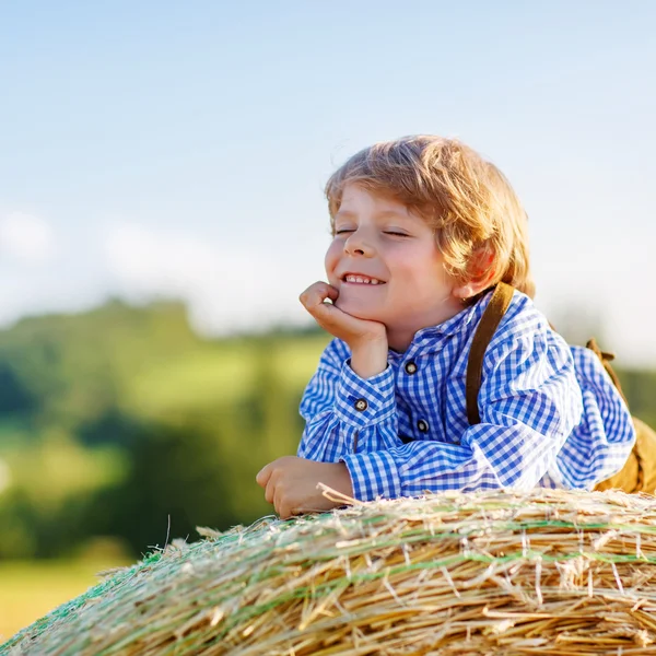 Divertido niño pequeño acostado en la pila de heno y sonriendo —  Fotos de Stock