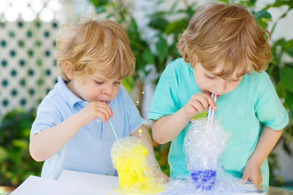 Två glada pojkar att göra experiment med färgglada bubblor — Stockfoto