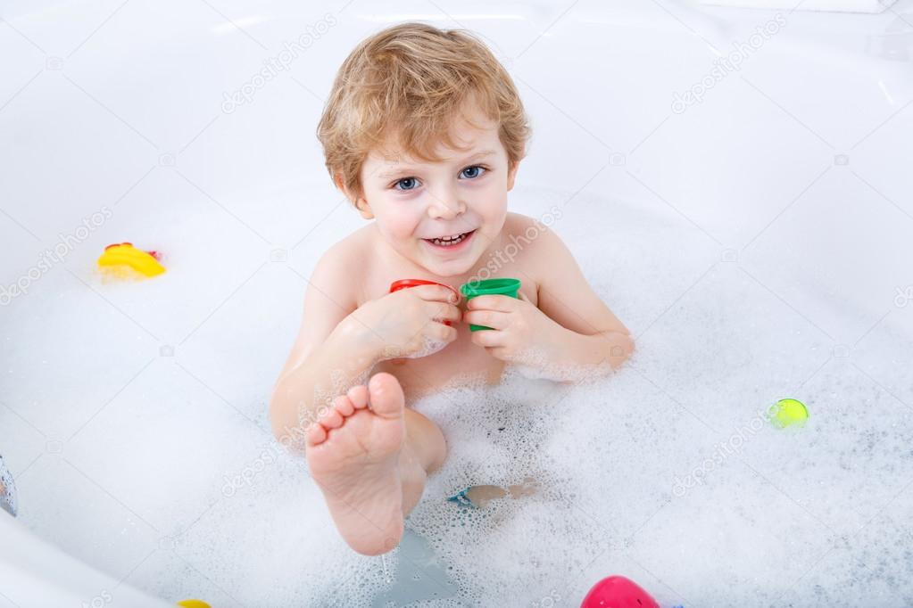 Adorable toddler boy having fun in bathtub