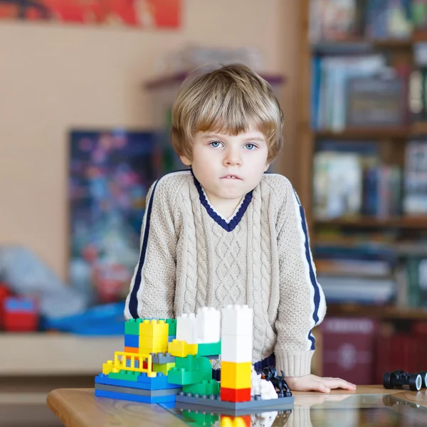 Enfant garçon jouer avec beaucoup de blocs en plastique coloré à l'intérieur — Photo