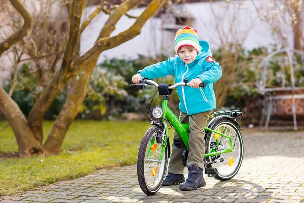 Pequeño niño preescolar montando con su primera bicicleta verde — Foto de Stock
