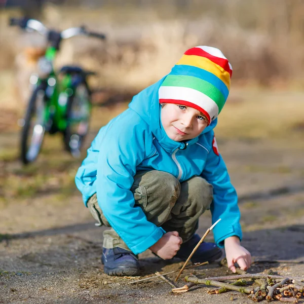 Lindo niño jugando con palos de madera en el parque de la ciudad, al aire libre — Foto de Stock