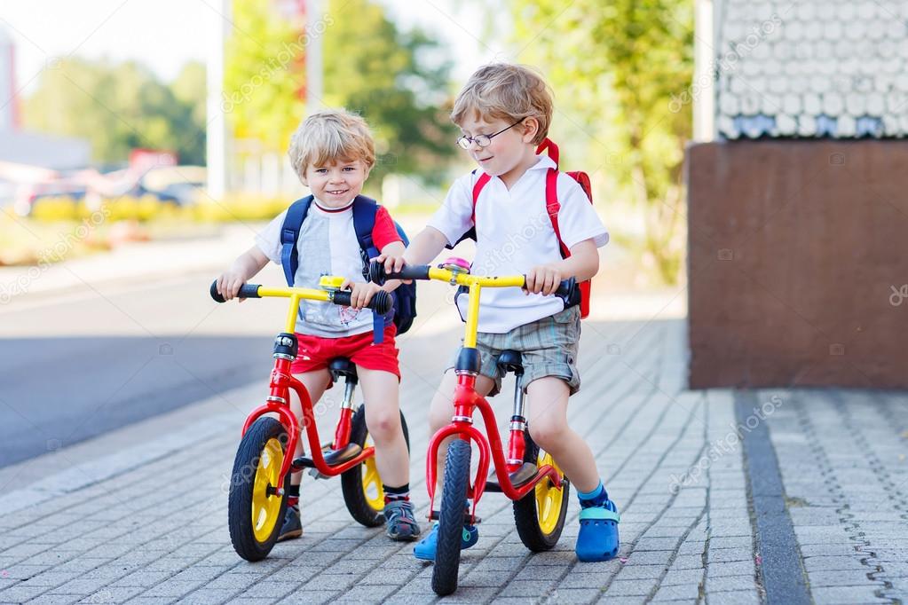 Two little siblings children having fun on bikes in city, outdoo
