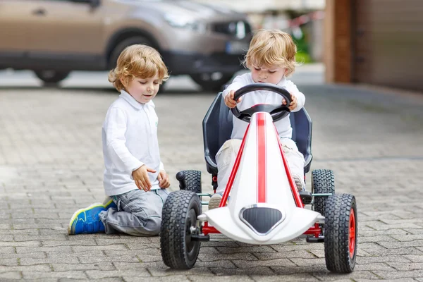 Dos hermanos felices jugando con el coche de juguete — Foto de Stock